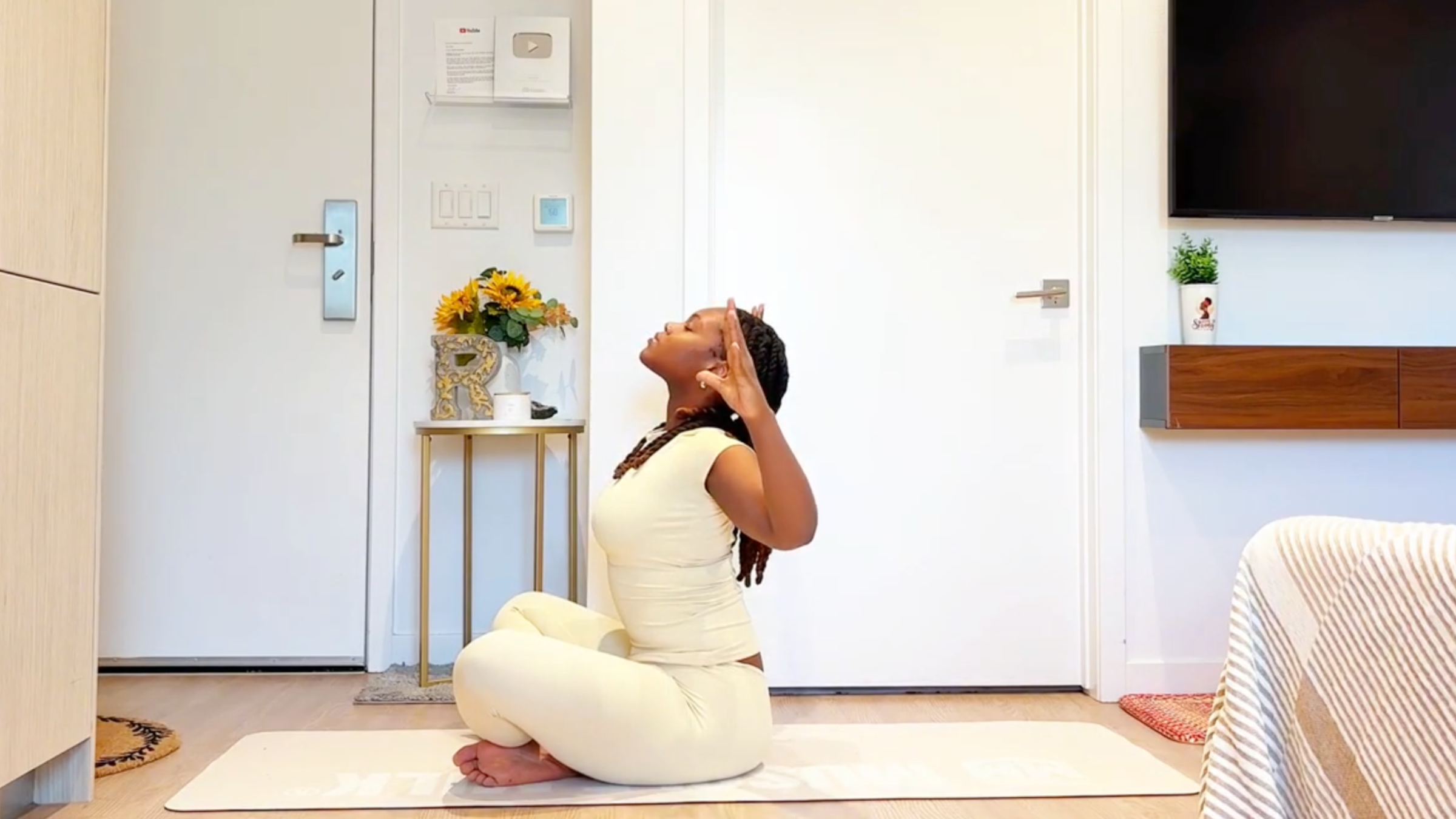 Yoga instructor Ramoni Overton doing Baby Backbend pose seated with arms in a cactus shape and chest lifted forward.